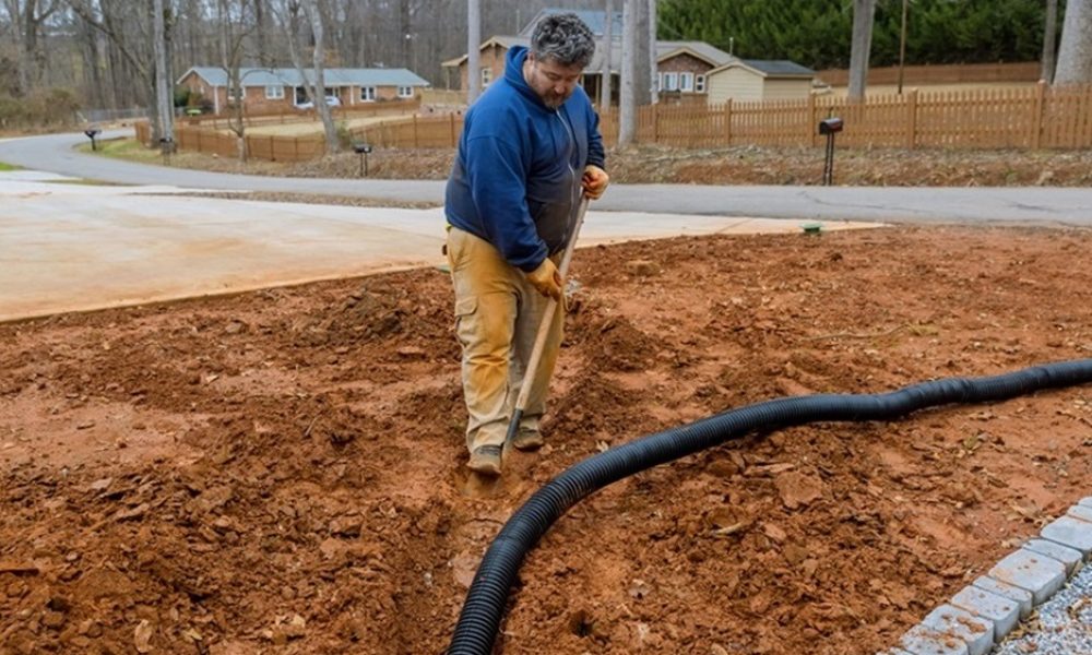 Worker digs trench to laying drainage pipe for rainwater during heavy rainfall